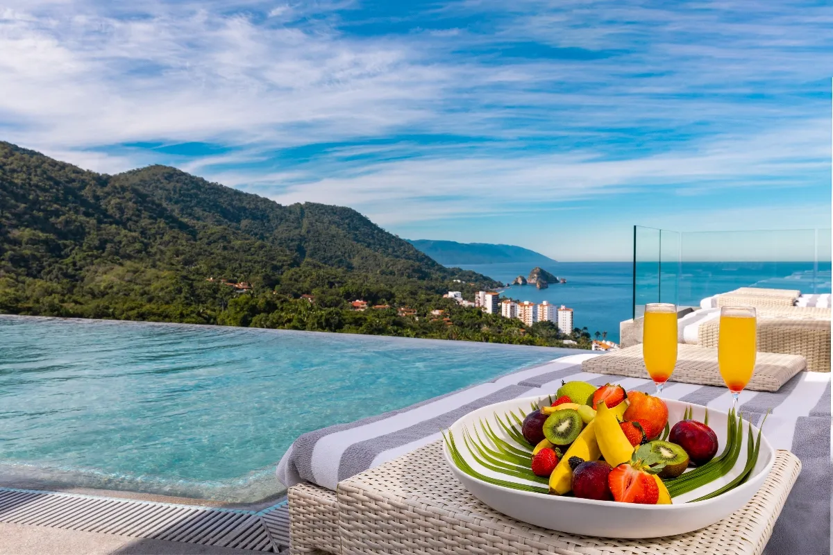 a plate of fresh fruit and cocktails at mousai vallarta rooftop